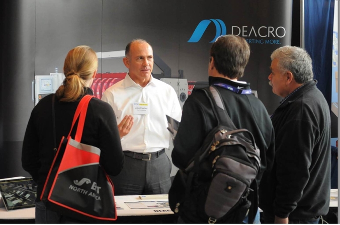 A Deacro employee talking with potential customers at a trade show.